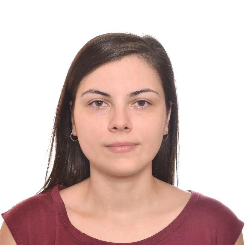 A portrait of a woman in her thirties with dark hair and brown eyes, wearing a dark red shirt